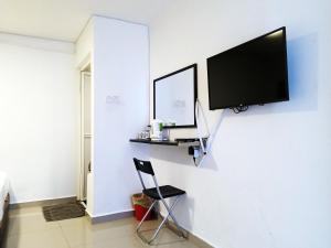 einen TV an einer Wand mit einem Stuhl in einem Zimmer in der Unterkunft Pengkalan Dua in Malakka