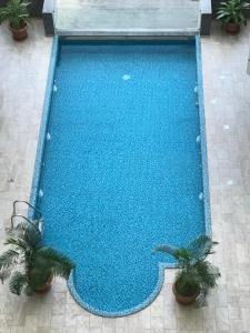 a large blue swimming pool with two plants at Obhur Residence 2 in Obhor