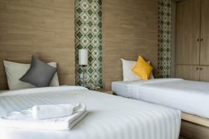 two beds in a hotel room with white sheets at Chinotel - SHA Plus in Phuket Town