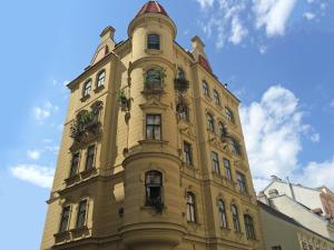 a tall yellow building with potted plants on it at 7th HEAVEN Vienna Center Apartments in Vienna