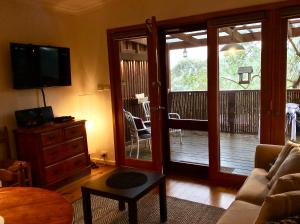 a living room with a television and a sliding glass door at The Green Room Wattle Glen in Wattleglen