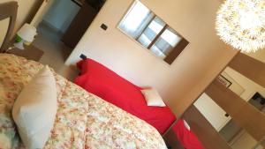 Casa del Sole - Sunshine Home في مارينا دي بيزا: غرفة نوم بسرير احمر وثريا