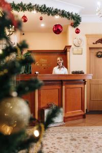 卡羅維發利的住宿－全境溫泉酒店，站在一个拥有圣诞装饰的房间的柜台后面的人