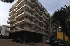 - un grand immeuble avec des voitures garées devant dans l'établissement Central loft Des Etrangers, à Sanremo