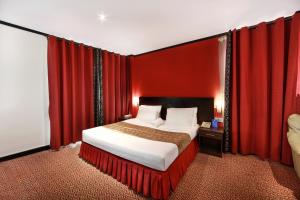 a bedroom with a large bed with red curtains at Manhattan Avenue Hotel in Dubai