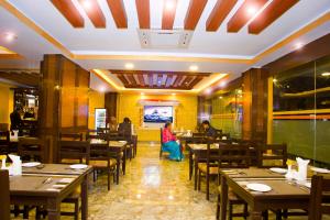 a dining room with wooden tables and people sitting in it at Hotel Yellow Pagoda Pokhara in Pokhara