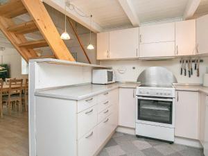 a kitchen with white cabinets and white appliances at Holiday Home Grævlingevej II in Mosevrå