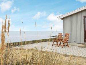 2 krzesła i stół na patio z widokiem na ocean w obiekcie Holiday home Farsø w mieście Sundsøre
