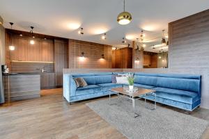 a living room with a blue couch and a table at Staywin Prime Apartments Chmielna in Gdańsk