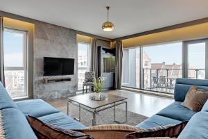 a living room with a blue couch and a tv at Staywin Prime Apartments Chmielna in Gdańsk