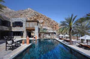 a swimming pool in front of a resort at Six Senses Zighy Bay in Dibba
