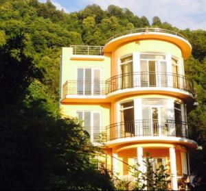 żółty dom na wzgórzu z drzewami w obiekcie Royal House w mieście Kvariati