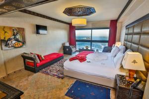 エッサウィラにあるリャド ミモウナのベッドルーム(大型ベッド1台、赤いソファ付)
