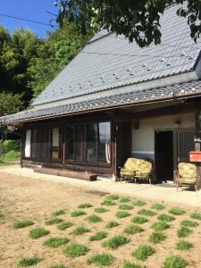 una casa con un porche con 2 sillas en un patio en 楓 -Kaede-, en Ōuda