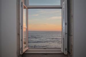 an open window with a view of the ocean at Liiiving in Porto - Luxury Beachfront Apartments in Porto