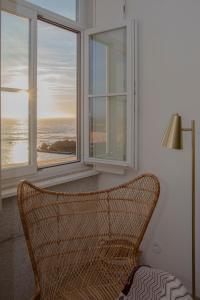 a wicker chair sitting in front of a window at Liiiving in Porto - Luxury Beachfront Apartments in Porto