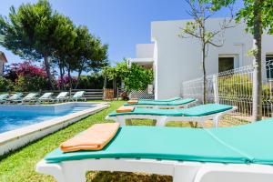 uma fila de cadeiras azuis e brancas junto a uma piscina em Villa 715 - our Albufeira holiday retreat em Albufeira