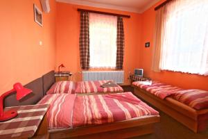 two beds in a room with orange walls and windows at Hotel Astoria with private skibus in Janske Lazne
