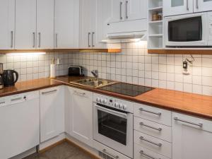 uma cozinha com armários brancos, um fogão e um lavatório em Holiday Home Karhunvartijan linna b14 by Interhome em Ruka