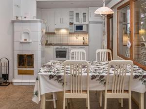 uma cozinha com uma mesa com 4 cadeiras e uma cozinha com armários brancos em Holiday Home Karhunvartijan linna b14 by Interhome em Ruka