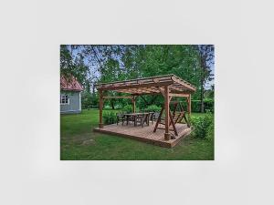 a wooden gazebo with a picnic table and benches at Holiday Home Villa ilmari by Interhome in Torvoila