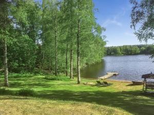a picnic area next to a lake with trees at Holiday Home Villa siesta by Interhome in Torvoila