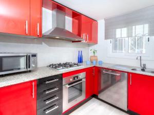サン・アントニオ・デ・カランジャにあるHoliday Home Marisol by Interhomeの赤いキッチン(ステンレス製の電化製品、赤いキャビネット付)