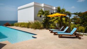 un gruppo di sedie con ombrellone accanto alla piscina di THE VILLAS at THE HORNED DORSET PRIMAVERA a Rincon