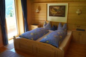 1 cama con almohadas azules en una habitación con ventana en Ferienwohnung - Schmirnerhof, en Brandberg