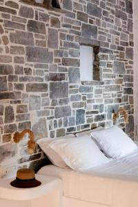 a bedroom with a brick wall and a bed with a hat at Zefi Hotel & Suites in Naousa