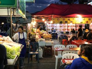 a woman standing in front of a market at night at P & H Residence NorthGate in Chiang Mai