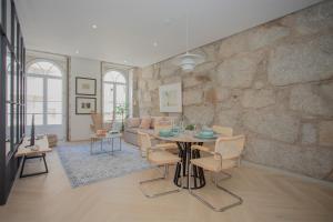a living room with a table and a stone wall at Liiiving in Porto - Luxury Beachfront Apartments in Porto