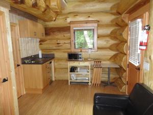 a kitchen in a log cabin with a table and a microwave at Porteau Cove Olympic Legacy Cabins in Furry Creek