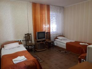 a hotel room with two beds and a television at Hotel Gostynnyi Dvir in Sharhorod