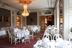 un comedor con mesas y sillas blancas y una lámpara de araña en Södertuna Slott, en Gnesta