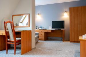 a room with a desk with a television and a mirror at Hotel U Zygmuntów in Leżajsk