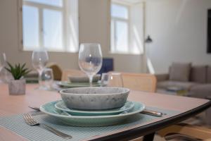 a table with a bowl and plates and wine glasses at Liiiving in Porto - Luxury Beachfront Apartments in Porto