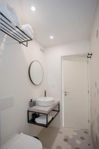 a bathroom with a sink and a toilet and a mirror at Liiiving in Porto - Luxury Beachfront Apartments in Porto