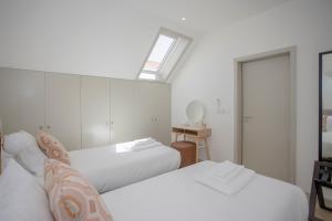 a white bedroom with two beds and a skylight at Liiiving in Porto - Luxury Beachfront Apartments in Porto