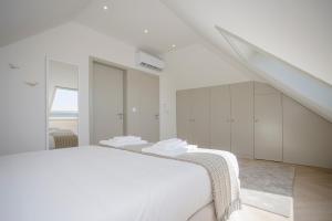a white bedroom with a white bed and a staircase at Liiiving in Porto - Luxury Beachfront Apartments in Porto