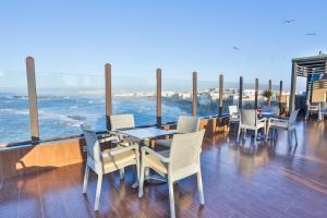 a patio with tables and chairs and the ocean at Riad Mimouna in Essaouira