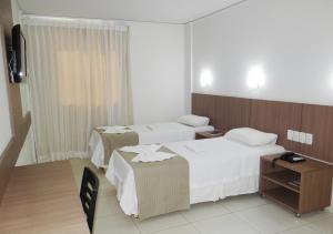 una camera d'albergo con due letti e una televisione di Oasis Hotel a Cajazeiras Altre 35 foto