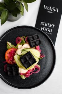 a black plate with food on a table at Wasa Resort Hotel, Apartments & SPA in Pärnu