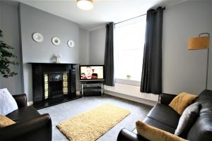a living room with a couch and a tv at Nelson By The Docks Serviced Apartments by Roomsbooked in Gloucester