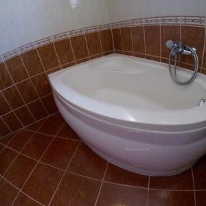 a white bath tub in a tiled bathroom at Dávid Apartman in Gárdony