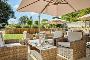 a patio with wicker chairs and tables with umbrellas at Les Villas d'Arromanches, Teritoria in Arromanches-les-Bains