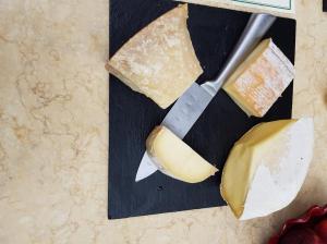 un bloc de fromage et un couteau sur une planche de découpe dans l'établissement Sous L'Olivier, à Menton