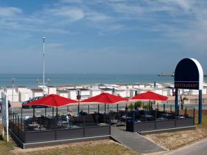 a restaurant with red umbrellas on the beach at Hôtel De La Plage in Calais