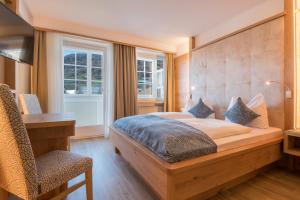 a bedroom with a bed and a desk and a chair at Hotel Lamm in Vipiteno