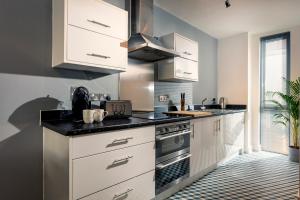 a kitchen with white cabinets and a black counter top at PENTHOUSE Plymouth Apartment- Sea View- Sleeps 7 - Private Parking - Habita Property in Plymouth